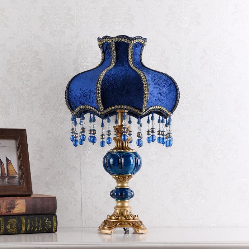 A vintage navy and gold bedroom lamp on a console with books